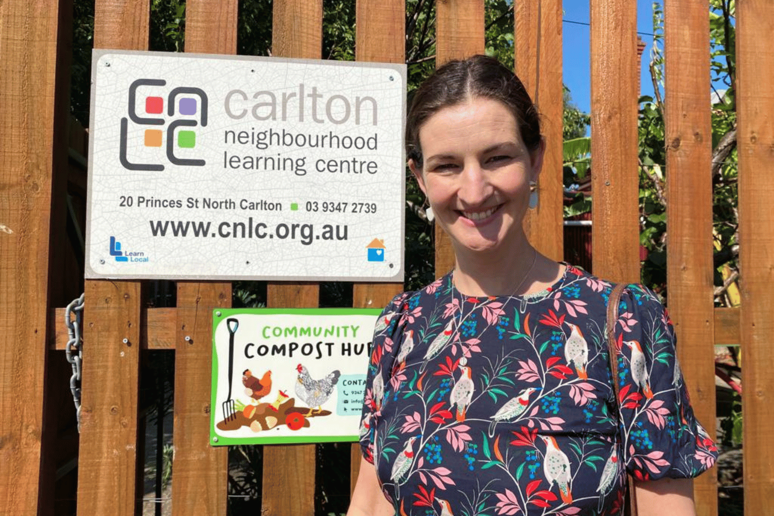 Ellen Sandell MP standing next to a sign for Carlton Neighbourhood Learning Centre