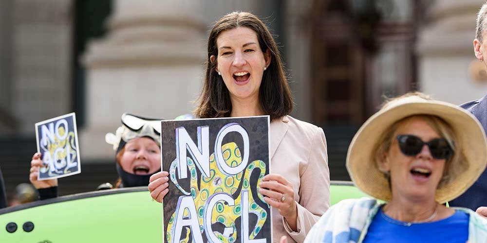 Ellen at a rally holding up a sign that says 'No AGL'