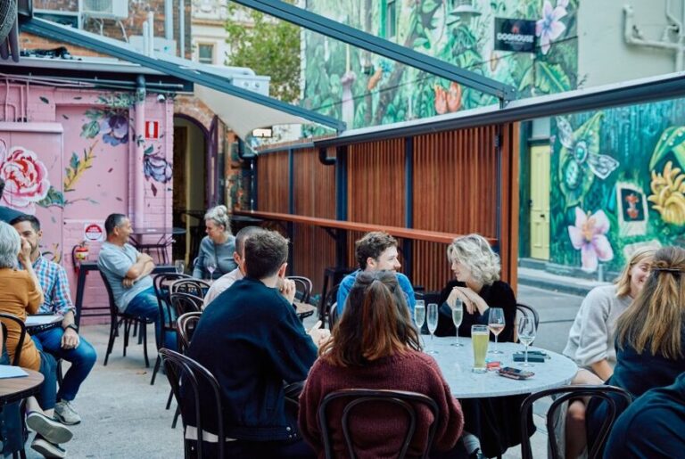 An open air beer garden with people sitting around drinking and talking